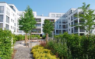 This residential complex in Scharnhäuser Park near Stuttgart has lush greenery in its courtyards, concealing the underground car park below. Green courtyard with shrubs, bushes, trees and playground, surrounded by residential blocks